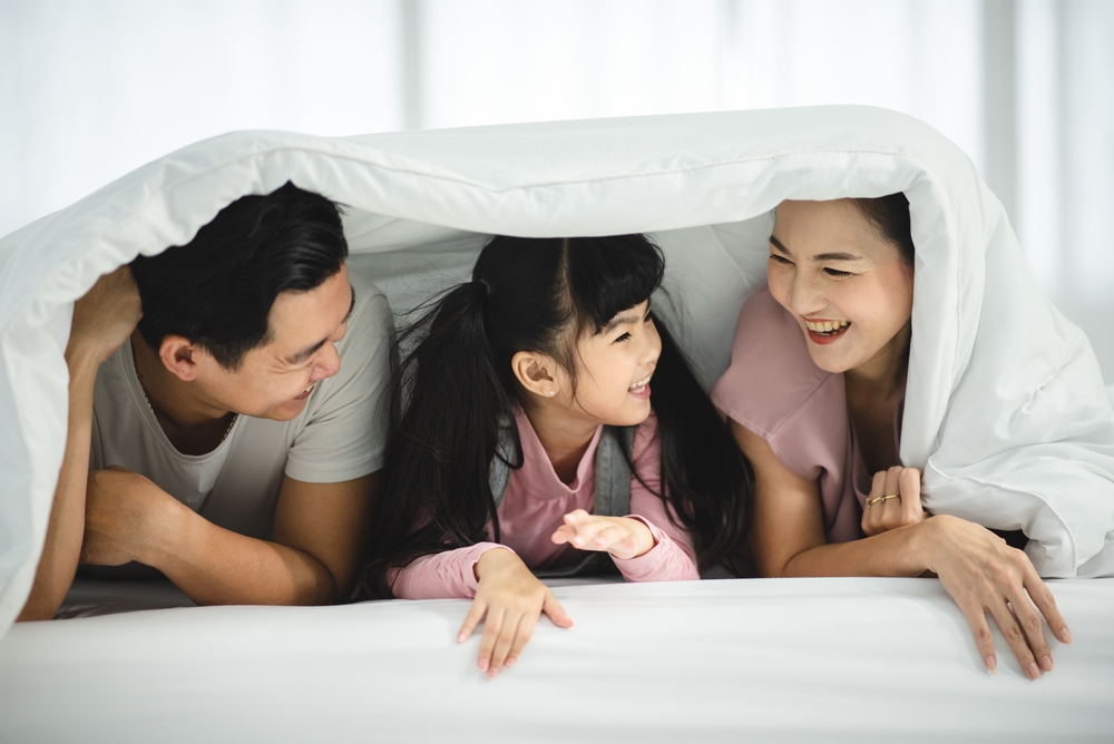 parents and child hiding and laughing under the blankets