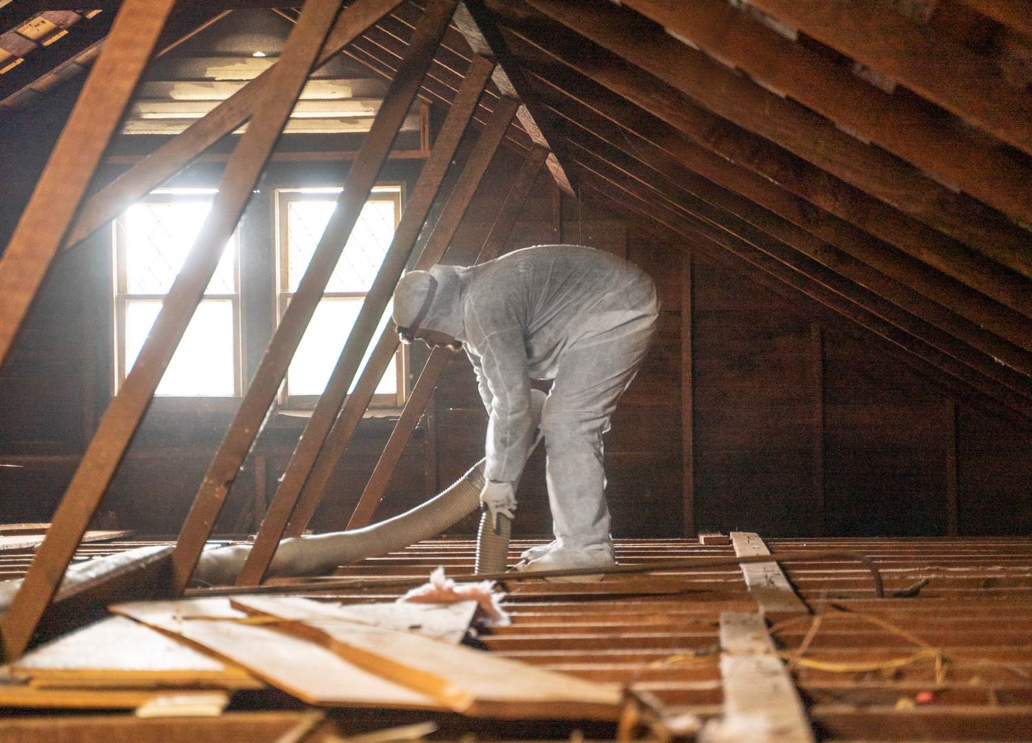 mean in a white hazard suit and face mask repairing air ducts in an attic.